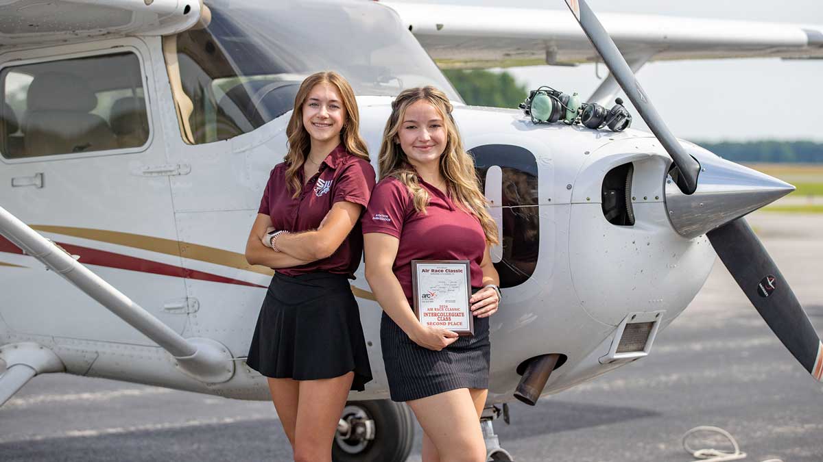 Two female students in front of a plane